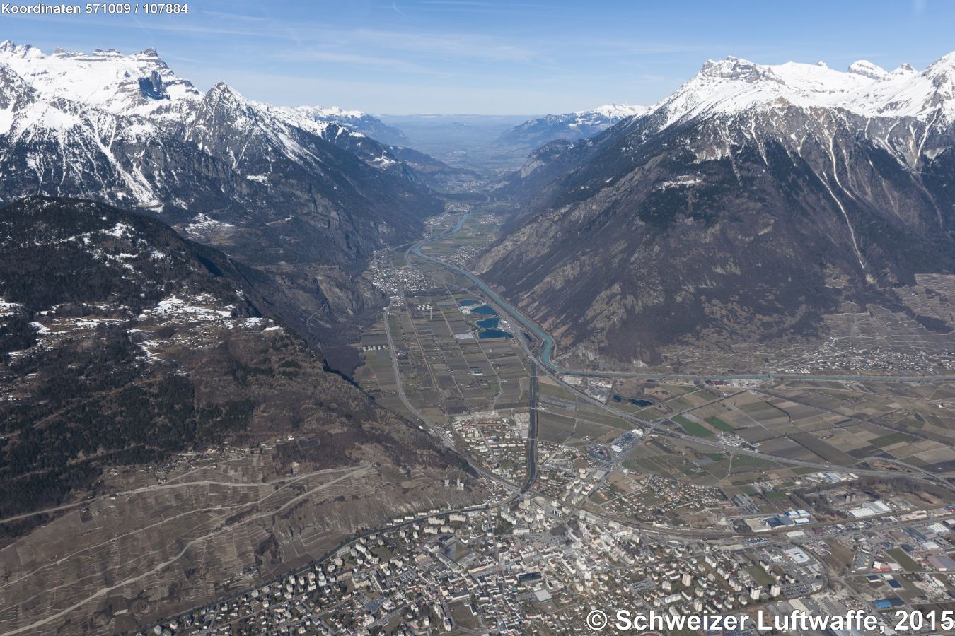Martigny (Position: 2'571'662.91, 1'106'178.66), Blickrichtung Nord Richtung Genfersee. Gegen den linken Bildrand: Strasse mit Kehrschleifen nach 'Le Sommet des Vignes'. Autobahn A9 durchläuft die Bilddiagonale. Am rechten Bildrand unten: Abzweigung 22 der A21 zum' Grossen St. Bernard'. Gebirge rechts im Bild: 'Dents de Morcles', links im Bild 'Dent du Midi'. Blick Rhone-abwärts nach Vernayaz und St-Maurice. - Dorf am rechten Bildrand Mitte: Fully.